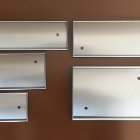 Alumínium profilos tábla, műanyag zárókupakkal, PET előlappal. Irodaházakba, hivatalokba ajánlott, felfúrható vagy felragasztható névtábla, széles méretválasztékban.