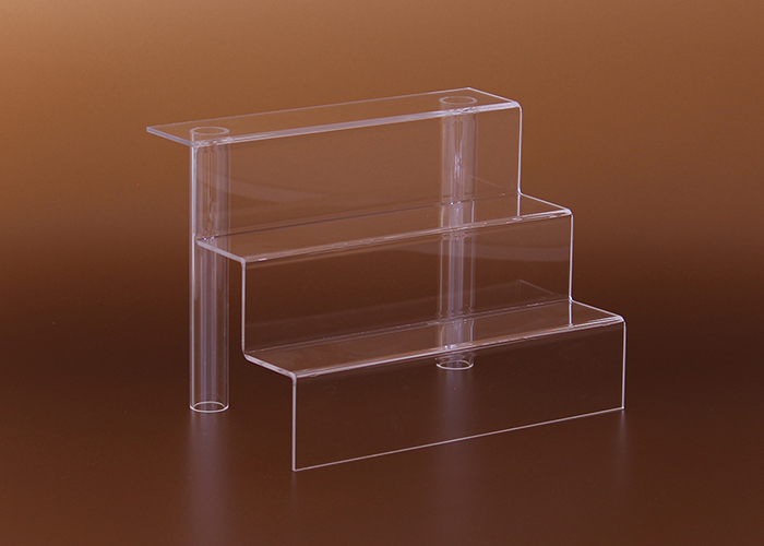 Háromszintes plexi áruemelő, amely lehetővé teszi több termék áttekinthető és esztétikus kihelyezését. Ideális polcokra, bemutatóasztalokra és üzlethelyiségekbe, ahol fontos a látványos és rendezett megjelenés.