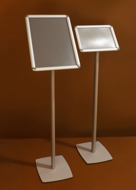 Fém lábra szerelt várakoztató tábla pattintó alumínium keretes plakáttartóval, amely stabil és könnyen használható megoldást biztosít információk, tájékoztatók és ajánlatok esztétikus bemutatására irodákban, üzletekben, várótermekben és közösségi terekben.