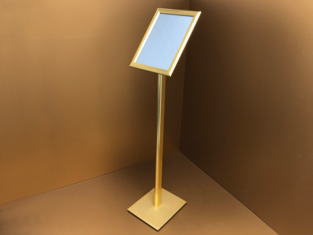 Fém lábra szerelt várakoztató tábla pattintó alumínium keretes plakáttartóval, amely stabil és könnyen használható megoldást biztosít információk, tájékoztatók és ajánlatok esztétikus bemutatására irodákban, üzletekben, várótermekben és közösségi terekben.